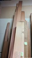 Tall stack of various lumber boards leaning against wall