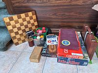 Overall lot view showing board games stack, wood board, ball sets and cases