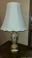 Full view of porcelain lamp with shade on table