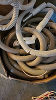 Top view of box showing coiled vacuum hoses, light grey ribbed with cuffs visible
