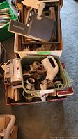 Overview of three boxes with green bin of vacuum accessories, brushes, white handle visible