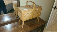 Closed view of wooden cantilever sewing box on dresser