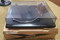 Full view of Yamaha TT-300 U turntable with dust cover in place, sitting on original box