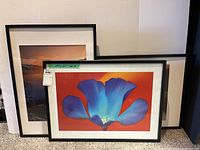 Three framed artworks leaning against wall