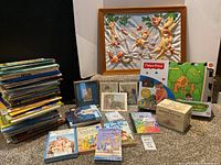 Stack of children’s books, framed art, Fisher-Price mat box, framed photos, Beatrix Potter box, CD
