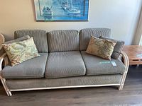 Front view of rattan couch, cushions and pillows visible