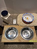 Overview of treat jar, ceramic bowl on mat, raised feeder with two stainless bowls