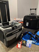 Group shot of wheeled luggage, gym bag, phone, toothbrush set and accessories