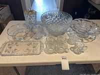 All glass items arranged on table including punch bowl, cups, trays, bowls and vase