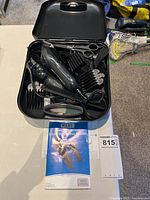 open case showing clipper, guards, scissors, comb and manual