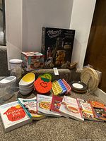 Full view of lot showing jars, boxed gadget, bowls, storage containers, plates, cookbooks