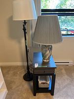 Floor lamp, table lamp on side table, basket on lower shelf