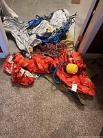 Pile showing red inflatable, foot pump, rope, part of canvas bag