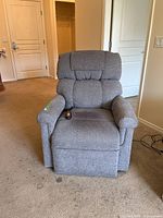 Front view of grey electric lift recliner chair with remote on seat