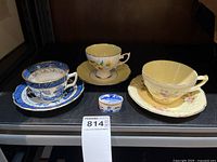 Three teacup sets and trinket box on shelf