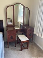 Front view of wood vanity with tri-fold mirror and bench