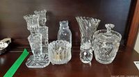 Seven clear cut glass/crystal pieces arranged on shelf