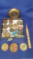 Group view showing coins in box, three larger coins, brass dish, letter opener, figurine