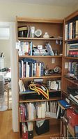 Full view of bookcase filled with books showing five shelves and wood grain