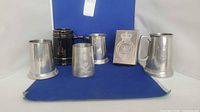 Group view of five tankards and metal stamp