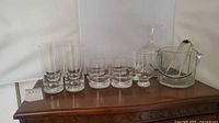 Front view of entire barware set showing highball, rocks, tasting glasses, carafe, ice bucket and tong