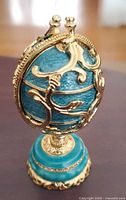 Closed egg on pedestal showing blue enamel and gold scrollwork