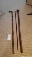 Three walking sticks laid side by side on carpet