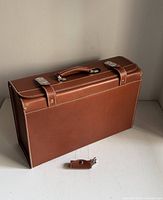Front view of brown leather briefcase showing handle, clasps and stitching