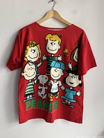 Full back view of red Peanuts graphic t-shirt on hanger