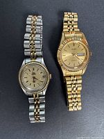 Two wristwatches laid flat, showing faces and bracelets