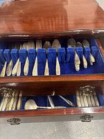 Upper drawer of cabinet showing forks, spoons in blue felt slots