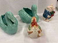 Four ceramic items: two aqua swan candlestick holders, rooster shaker, pig shaker