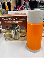 Boxed Via Veneto espresso maker beside orange Thermos flask