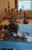Group shot showing both Lancini candelabras, Buddha bust on stand, cloche, bowls, fused glass plate, salad tongs, tribal mask