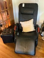 Full view of black faux leather massage recliner with ottoman and pillow
