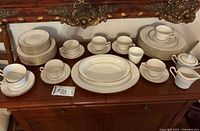 Full dinnerware set on buffet showing plate stacks, cups, saucers, platters, creamer, sugar bowl
