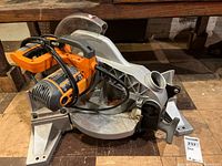 Left front view of Ridgid compound miter saw showing blade, motor housing, and base