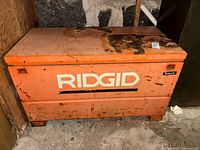 Front view of RIDGID orange 48" steel jobsite chest showing logo and rust on lid