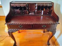 Front view of secretary desk showing upper cubbies, drawers, and carved details