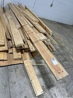 Pile of used 2x4 lumber pieces stacked on floor