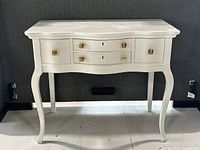 Front view of white painted solid wood desk with three drawers and brass pulls