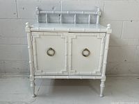 Front view of cabinet closed showing faux bamboo trim and brass ring pulls