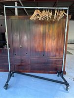 Full view of chrome garment rack with wooden hangers on bar