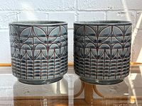 Front view of both matching ceramic planters on glass shelf