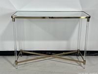 Front view showing mirrored top, brass frame, lucite legs, and stretcher