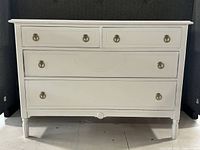 Front view of white four-drawer dresser showing overall condition and hardware