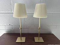 Front view of both brass lamps on wooden surface