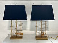 Both brass lamps with navy shades displayed side by side on table