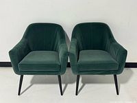 Front view of both emerald green velvet lounge chairs showing upholstery and leg style