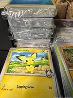 Stack of hard-sleeved cards beside unsleeved bulk showing Pichu card